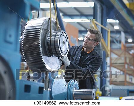 Stock Image - Engineer assembling industrial gearbox in engineering factory. Fotosearch