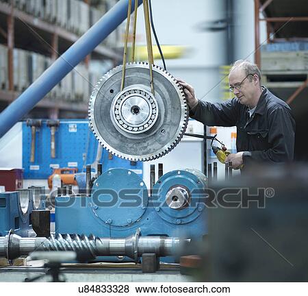 Stock Photo - Engineer assembling industrial gearbox in engineering factory. Fotosearch