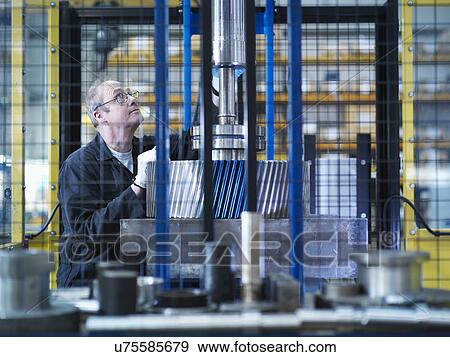Stock Photo - Engineer fixes gear to spindle in engineering factory. Fotosearch