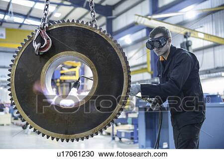 Engineer heat treats industrial gear in factory View Large Photo Image Stock Image - Engineer heat treats industrial gear in factory. Fotosearch