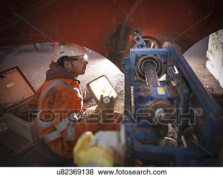 Stock Photo - Engineer reboring parts in engineering workshop. Fotosearch