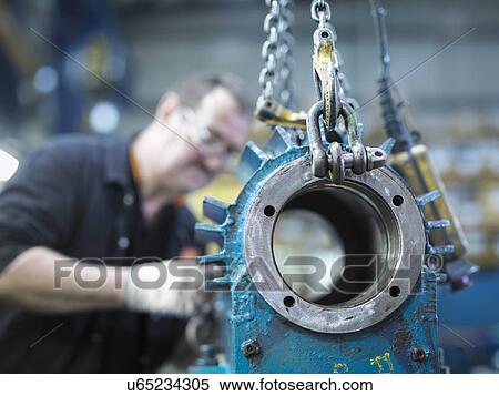 Stock Photography - Engineer repairs industrial gearbox in engineering factory. Fotosearch