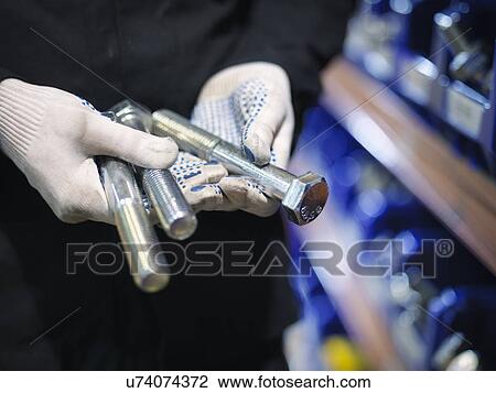 Stock Image - Engineer selecting bolts from store in engineering factory, close up. Fotosearch