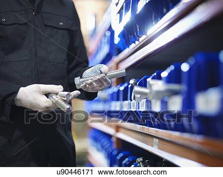 Stock Image - Engineer selecting bolts from store in engineering factory, close up. Fotosearch
