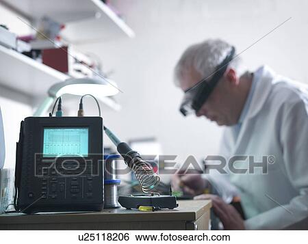 Engineer soldering prototype circuit board with oscilloscope in foreground View Large Photo Image Stock Photograph - Engineer soldering prototype circuit board with oscilloscope in foreground. Fotosearch