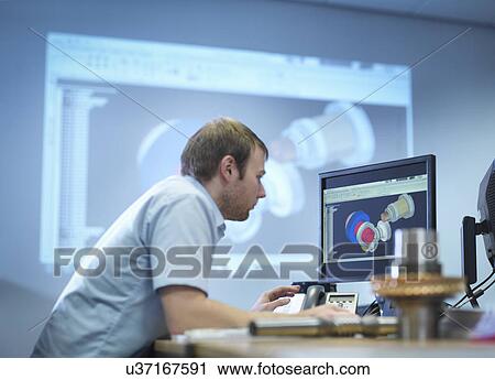 Stock Image - Engineer using computer aided design in factory office. Fotosearch