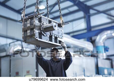 Engineer using crane to move industrial gearbox to paint works in engineering factory View Large Photo Image Picture - Engineer using crane to move industrial gearbox to paint works in engineering factory. Fotosearch