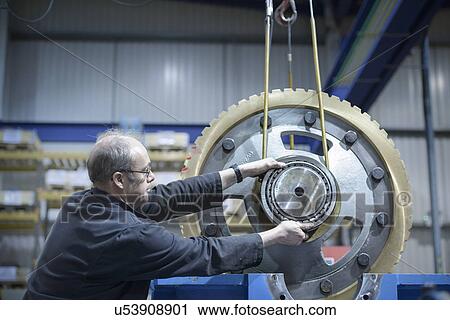 Engineer using crane to move large gear wheel in engineering factory View Large Photo Image Stock Image - Engineer using crane to move large gear wheel in engineering factory. Fotosearch