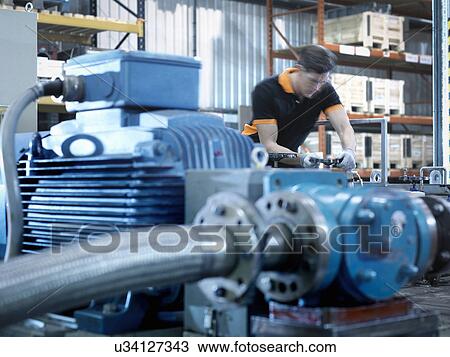 Stock Image - Engineer with industrial pump testing rig in factory. Fotosearch