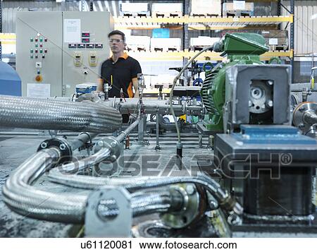 Stock Image - Engineer with industrial pump testing rig in factory. Fotosearch