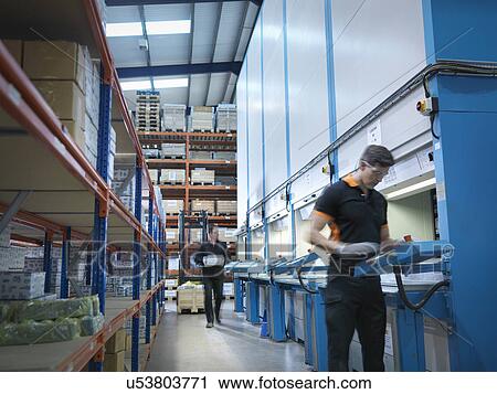 Stock Image - Engineers choose parts from automated store in factory. Fotosearch