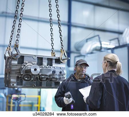 Picture - Engineers in discussion next to industrial gearbox in engineering factory. Fotosearch