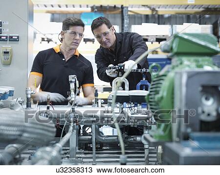 Stock Image - Engineers with industrial pump testing rig in factory. Fotosearch