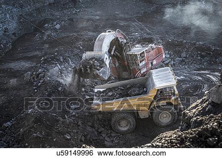 Stock Photograph - Excavator and dumper truck in void at surface coal mine. Fotosearch