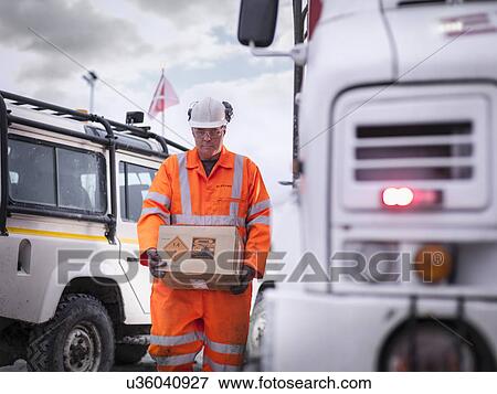 Stock Photo - Explosives expert carrying box in surface coal mine. Fotosearch