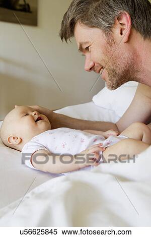 Stock Photography - Father and baby daughter on bed. Fotosearch