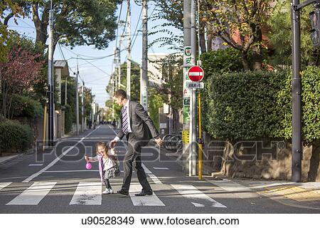 Stock Photo - Father and daughter crossing zebra crossing. Fotosearch