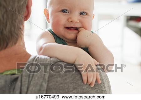 Father carrying baby daughter with finger in mouth View Large Photo Image Stock Photo - Father carrying baby daughter with finger in mouth. Fotosearch