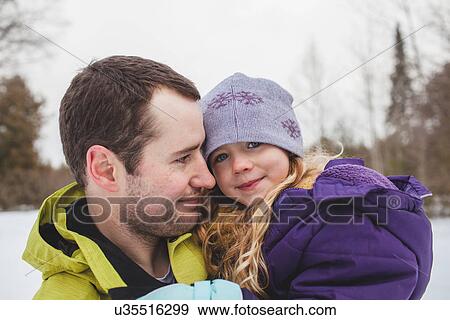 Stock Photo - Father holding daughter in snow. Fotosearch