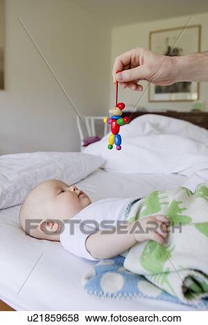 Stock Photo - Father holding wooden toy for baby daughter. Fotosearch