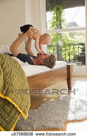 Father lifting baby daughter on bed View Large Photo Image Stock Photo - Father lifting baby daughter on bed. Fotosearch