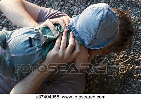 Stock Photo - Father lying on ground holding baby daughter. Fotosearch