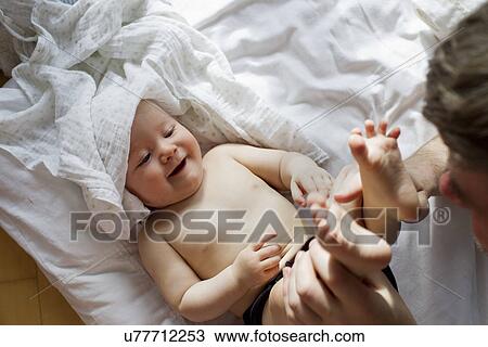 Stock Image - Father playing with baby daughter. Fotosearch