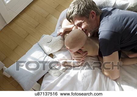 Stock Photograph - Father playing with baby daughter. Fotosearch