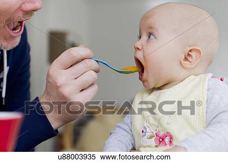 Father spoon feeding baby daughter View Large Photo Image Stock Photography - Father spoon feeding baby daughter. Fotosearch