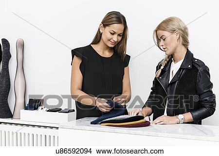 Female colleagues examining beanie hats View Large Photo Image Picture - Female colleagues examining beanie hats. Fotosearch