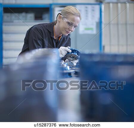 Stock Photograph - Female engineer assembling small parts of industrial gearbox in engineering factory. Fotosearch