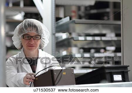 Stock Photo - Female scientist monitoring test in laser laboratory. Fotosearch