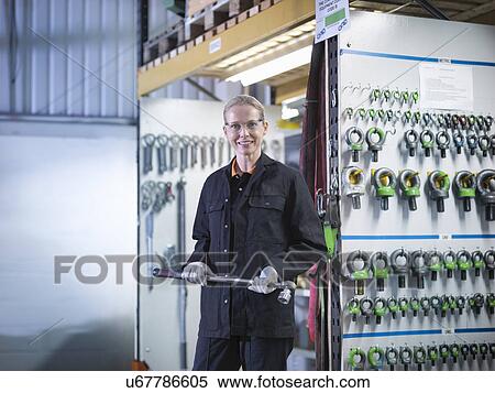 Stock Photography - Female worker in engineering factory holding lifting gear, portrait. Fotosearch