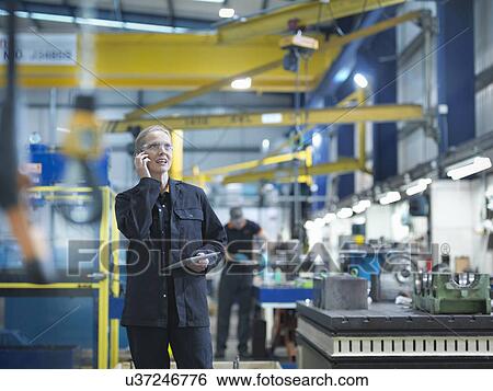 Female worker using mobile phone in engineering factory View Large Photo Image Stock Photograph - Female worker using mobile phone in engineering factory. Fotosearch