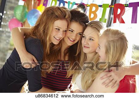 Stock Image - Four teenage girls celebrating at birthday party. Fotosearch