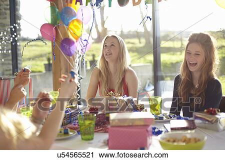 Stock Image - Four teenage girls celebrating with bubbles at birthday party. Fotosearch