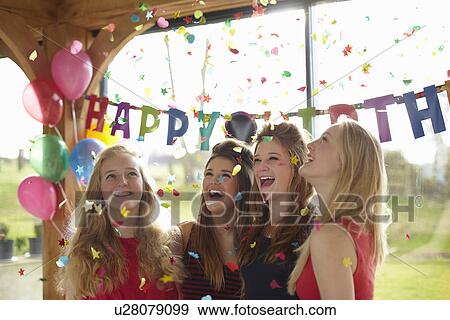 Stock Photo - Four teenage girls enjoying confetti at birthday party. Fotosearch