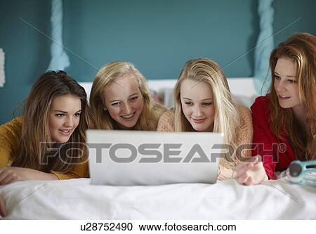 Four teenage girls looking at laptop in bedroom View Large Photo Image Stock Image - Four teenage girls looking at laptop in bedroom. Fotosearch