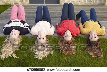 Stock Image - Four teenage girls lying on patio and looking back. Fotosearch