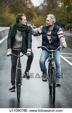 Friends cycling on street View Large Photo Image Stock Photograph - Friends cycling on street. Fotosearch