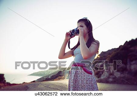 Stock Image - Girl taking photographs at dusk, Kas, Turkey. Fotosearch