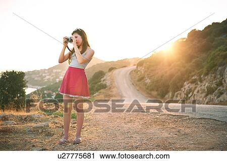 Stock Image - Girl taking photographs at sunset, Kas, Turkey. Fotosearch
