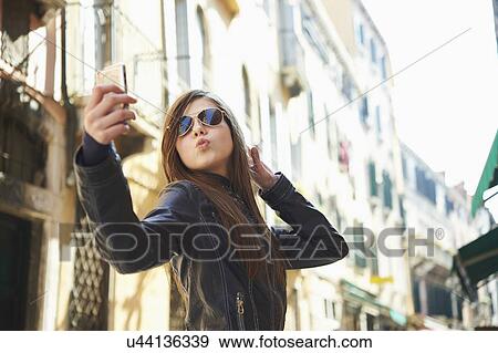 Stock Photo - Girl taking selfie on smartphone, Venice, Italy. Fotosearch
