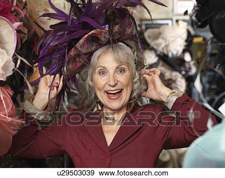 Glamorous senior woman trying on hat View Large Photo Image Stock Photo - Glamorous senior woman trying on hat. Fotosearch