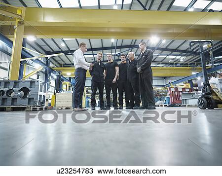 Stock Image - Group of engineers and apprentices in engineering factory. Fotosearch