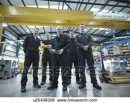 Stock Photo - Group of engineers and apprentices in engineering factory, portrait. Fotosearch