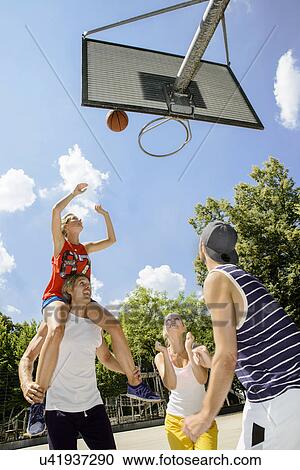 Stock Image - Group of friends having fun playing basketball. Fotosearch