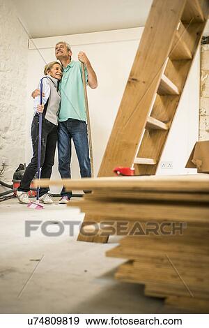 Stock Photo - Happy senior couple holding brooms. Fotosearch