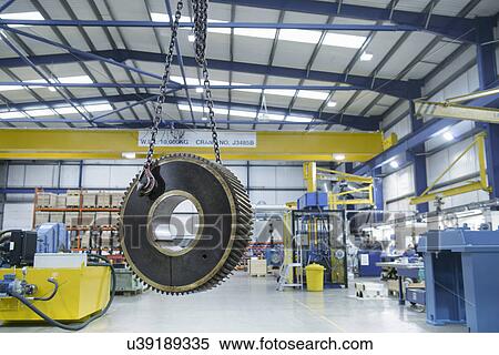 Stock Photography - Heavy engineering gear hanging from crane in factory. Fotosearch