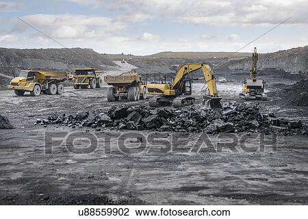 Stock Image - Machines working in surface coal mine. Fotosearch
